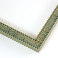 An understated, decorative frame. This slim molding features a raised, uneven, vertical pattern on the face. It has been washed with a sea foam green paint, and the natural wood is visible along the profile and raised edges.