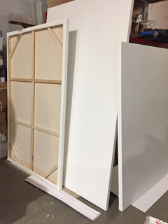 A large, square gallery wrapped canvas being mounted on a stretcher bar frame